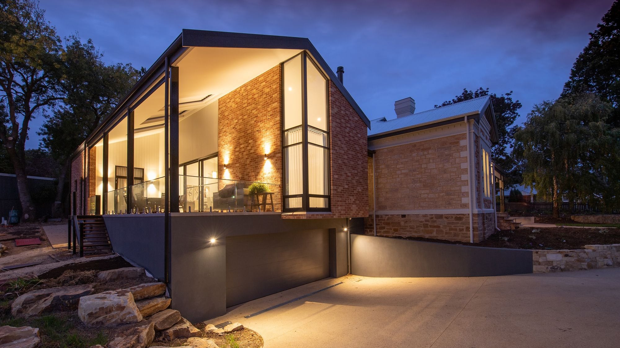 Residência moderna ao entardecer, com interiores iluminados e jardim
